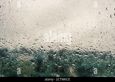 raindrops on the window pane with trees in the background. Rainy weather, background Stock Photo