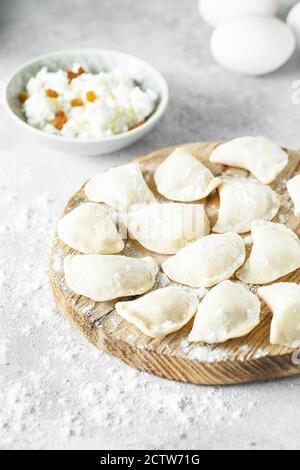 uncooked cottage cheese dumplings on a board with flour Stock Photo