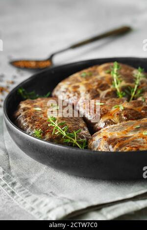 Delicious grilled liver meatballs with buckwheat in a natural casing. Liver patties on the little frying pan served with thyme. Food photography. Stock Photo