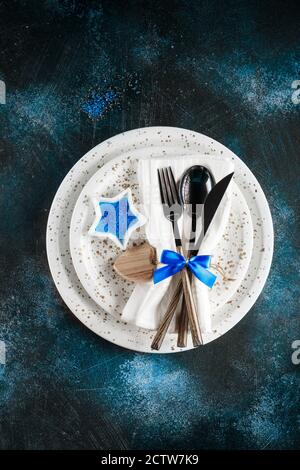 Festive table place setting. Crockery, cutlery and goblet glass on a dark blue textured background with copy space. Christmas Xmas New Year holiday ba Stock Photo