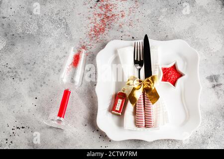Christmas table place setting with square plate, cutlery with festive decorations gold ribbon, bauble red telephone box, star-shaped bowl with red sug Stock Photo