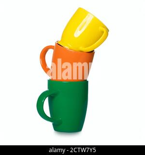 Stack of three motley cups isolated on white background. Three coffee mugs - orange, green and yellow Stock Photo