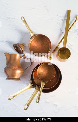 Copper utensils on the white background. Vintage copper cookware - cocottes, creamer and accessories for coffee. Stock Photo