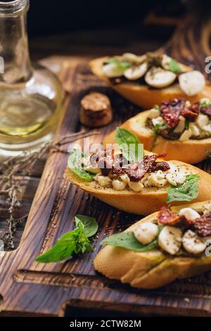 sandwich with mozzarella cheese, pesto, sun-dried tomatoes and basil and thyme, served on the wooden board Stock Photo