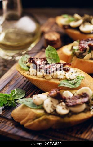 sandwich with mozzarella cheese, pesto, sun-dried tomatoes and basil and thyme, served on the wooden board Stock Photo