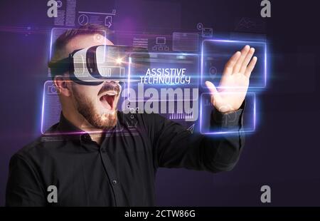 Businessman looking through Virtual Reality glasses with ASSISTIVE TECHNOLOGY inscription, new technology concept Stock Photo