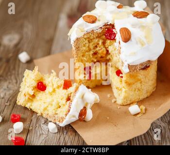 Easter composition. Easter cake decorated with almond petals and marshmallows on a rustic wooden background. Stock Photo