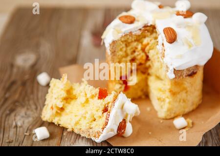 Easter composition. Easter cake decorated with almond petals and marshmallows on a rustic wooden background. Stock Photo