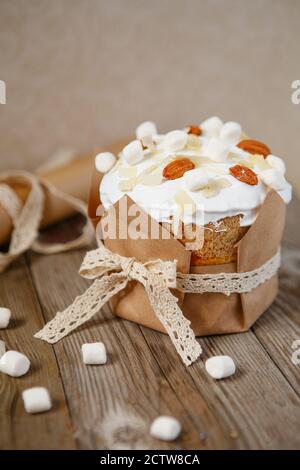 Easter composition. Easter cake decorated with almond petals and marshmallows on a rustic wooden background. Stock Photo