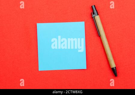 Blue sheet of writing paper, ballpoint pen on red background, copy space, top view Stock Photo