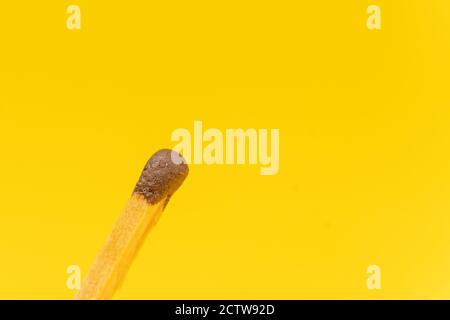 Match with a brown head on a yellow background with copy space, macrophotography Stock Photo