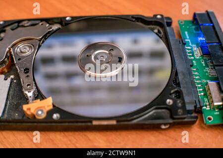 The hard disk is lying on the table, blinking and spinning the disk. Work of a hacked hard drive inside. Computer security. Internal structure of the Stock Photo