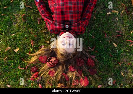 A beautiful girl lies on the ground with autumn leaves in her hair. Stock Photo