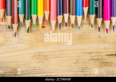Background with colored pencils and space for copying space on a wooden background, top view. Artistic background Stock Photo