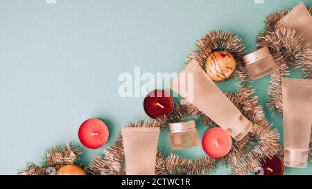 Top view composition of small travelling bottles and jars for cosmetic products with Christmas decorations. Facial skin care concept. copy space Stock Photo
