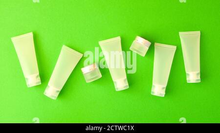 Top view composition of small travelling bottles and jars for cosmetic products on green background. Facial skin care concept. copy space Stock Photo