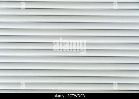 Background of gray-white horizontal metal bands. Roll-up curtains and garage doors. Protecting Windows and doors from intruders. Stock Photo