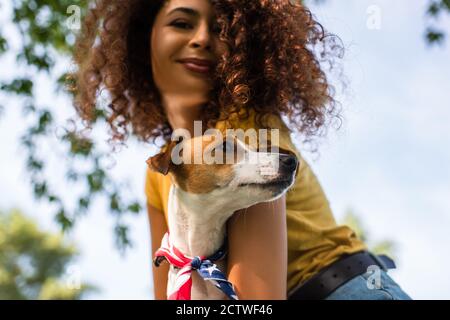 low angle view of joyful, curly woman holding jack russell terrier dog Stock Photo