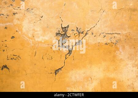 Grunge plastered old wall with cracks. Background image of yellow plaster. High quality photo Stock Photo