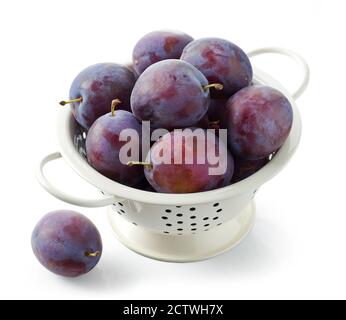 fresh ripe plums in colander isolated on white background Stock Photo