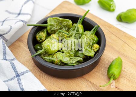 Cooked Padron peppers in a a bowl on wooden table. Traditional Spanish appetizer Stock Photo