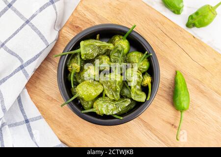 Top view of Cooked Padron peppers in a a bowl on wooden table. Traditional Spanish appetizer Stock Photo