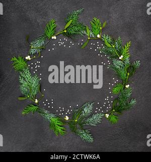 Mistletoe & cedar cypress winter solstice & Christmas wreath with silver balls decorations on grey grunge background. Abstract design Stock Photo