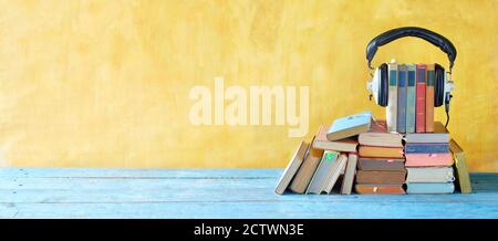 audio book concept with large heap of books and vintage headphones, good copy space Stock Photo