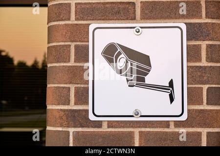 Sign showing CCTV camera on brick wall of building Stock Photo