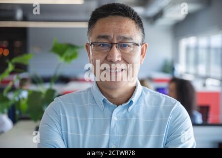 Portrait of smart casually dressed Asian male business creative wearing glasses smiling to camera. Creative business professional working in a modern Stock Photo
