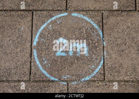 A painted sign on the pavement in North Wales, UK, - reminding the public about social distancing during the Coronavirus pandemic.  To keep a 2 metres Stock Photo