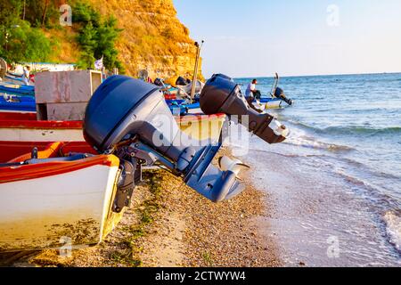 View on propellers of motorboats on the sandy beach, foamy waves are splashing the shore Stock Photo