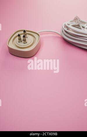 Vertical shot of an electrical extension cord isolated on pink background Stock Photo