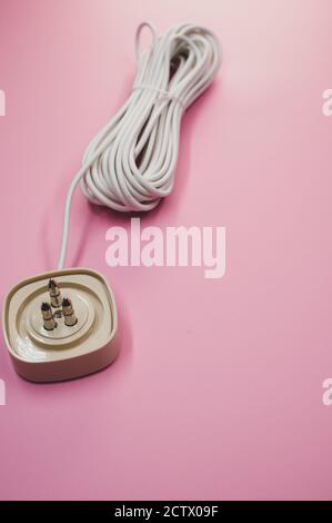 Vertical shot of an electrical extension cord isolated on pink background Stock Photo