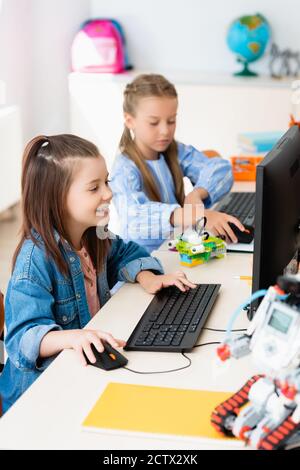 Selective focus of schoolgirls using computers near robots in stem school Stock Photo