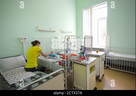 At a hospital room: hospital beds, nightstands, child lying in a hospital bed, mother taking care of it. Children's Cardiac Center. May 18,2018. Kiev Stock Photo