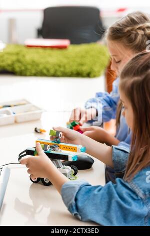 Selective focus of schoolkids playing with building blocks while modeling robot in school Stock Photo