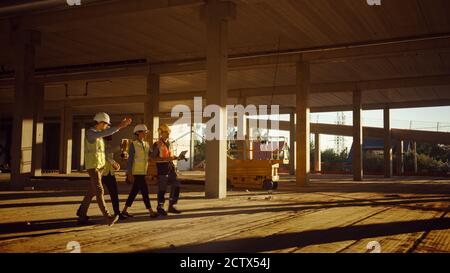 Diverse Team of Specialists Walk Through Garage Level of Industrial Commercial Building Construction Site. Real Estate Project with Civil Engineer Stock Photo