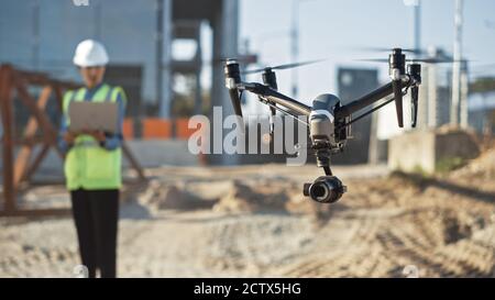 Specialist Controlling Drone on Construction Site. Architectural Engineer or Inspector Fly Drone on Building Construction Site Controlling Quality Stock Photo