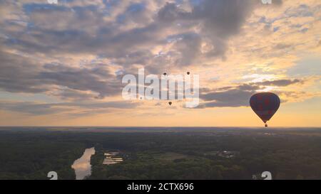Aerial drone view of colorful hot air balloon flying over green park in small european city at summer sunset, Kiev region, Ukraine Stock Photo