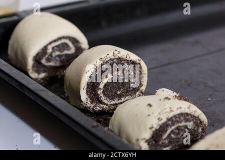 Pieces of dough roll with poppy filling. Lie on a baking sheet. Cooking buns. Stock Photo