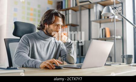 Handsome Long Haired Hispanic Businessman Sitting at His Desk in the Office Works on a Laptop. Creative Developing New Software Unicorn Startup Stock Photo