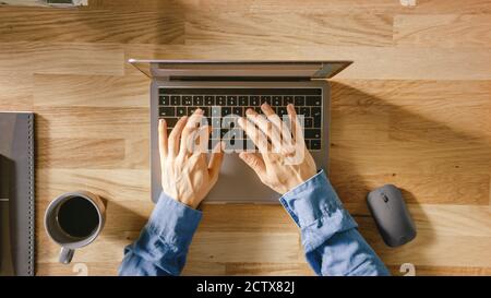 Top View Close-up Shot of a Man's Hands Typing on a Laptop Keyboard. Bright and Modern Theme. Stock Photo
