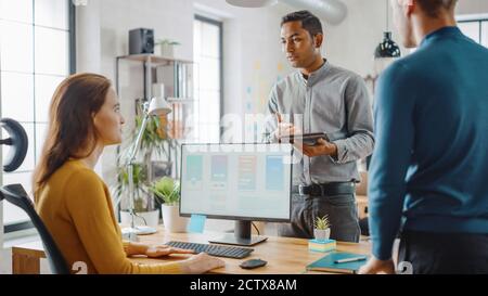 Three Mobile Software Developers Work on Desktop Computer, They Discuss Smartphone Application Design Use Touch Screen Digital Tablet. Modern Stylish Stock Photo