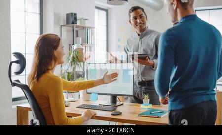 Three Mobile Software Developers Work on Desktop Computer, They Discuss Smartphone Application Design Use Touch Screen Digital Tablet. Modern Stylish Stock Photo
