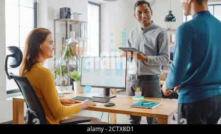 Three Mobile Software Developers Work on Desktop Computer, They Discuss Smartphone Application Design Use Touch Screen Digital Tablet. Modern Stylish Stock Photo