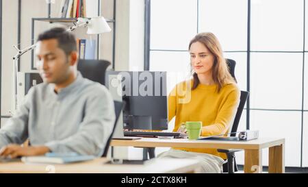 Handsome Indian Information Technology and Brilliant Female Data Specialist Sitting at Their Desks work on Desktop Computers. Modern Office with Stock Photo