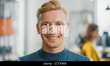 Portrait of Handsome Professional Caucasian Man Looking at the Camera and Smiling Charmingly. Successful Blonde Man Working in Bright Diverse Office. Stock Photo
