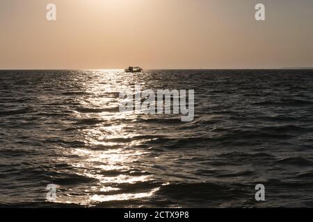 Lonely fishing ship trawler boat on ocean water. Calm clear sea sunny weather. Beautiful horizon of seascape Stock Photo