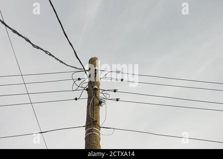 An old electric wooden pole with electricity cables hanging on it. Natural light. Stock Photo